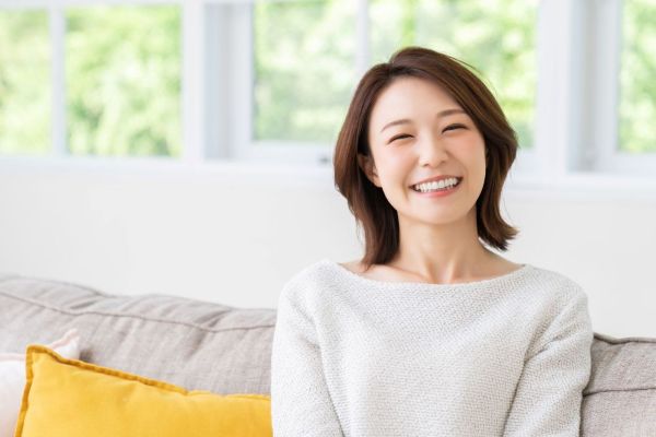 【お客様の声】REALTY ONEで理想のマイホームを購入され、笑顔でソファに座られているお客様の写真です。